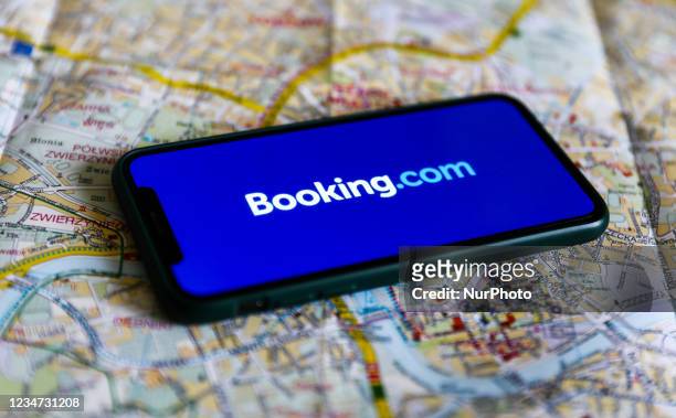 Booking.com logo displayed on a phone screen and a map of Krakow are seen in this illustration photo taken in Krakow, Poland on August 17, 2021.