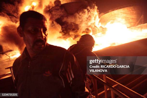 Libyan men watch as the main fuel depot in Libya's third largest city Misrata burns following a bombing by forces loyal to leader Moamer Kadhafi on...