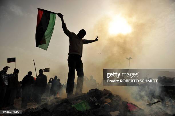 Resident of the north-central Libyan city of Benghazi stands atop a burning heap of books authored by Libyan leader Moamer Kadhafi at a local park of...