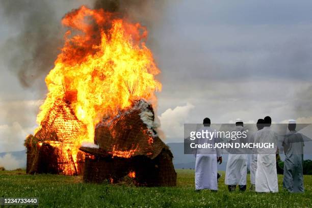 Darfur survivors watch as huts burn near Gleneagles, Scotland, 05 July 2005, in a re-enactment of the destruction of their homes by the Janjaweed...