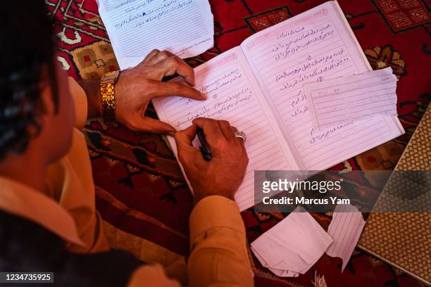 Ibrahim Amiri writes down lyrics to songs in his music workshop inside the Ghos Al-Din building, in Kabul, Afghanistan, Monday, May 17, 2021. A,oro...