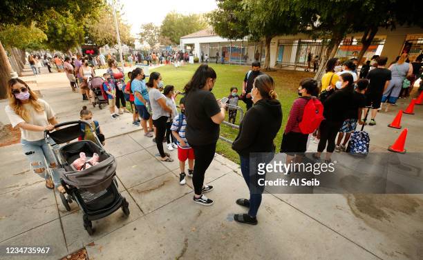 Parents and students form lines to check for the student name on a list using the Daily Pass website designed to issue pre-approved health clearances...