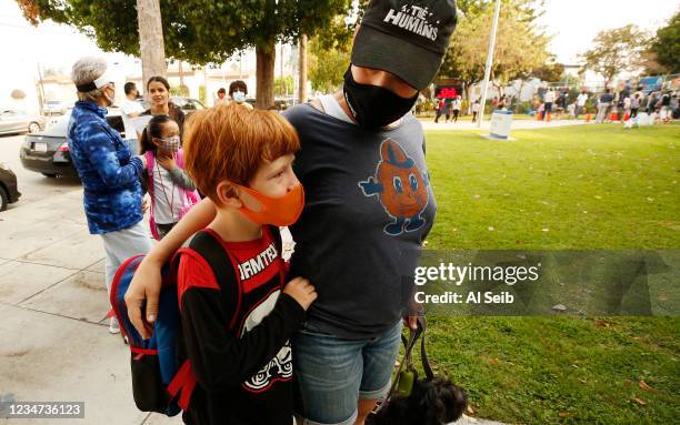 Third grade student Monty Eagan-Bloom wears a mask to match his hair color as he waits with his mother Daby Eagan as parents at Lankershim Elementary...