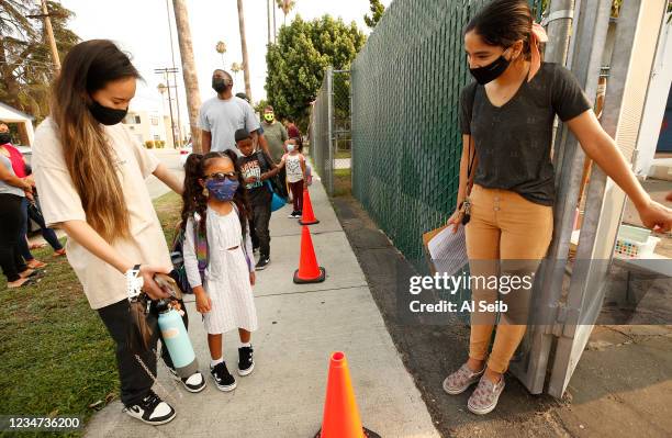 Kindergartner Rylee Doan with her mother Tiffany Doan-Evans checks in with Yazmin Magallon, right, Primary Promise Aide at Lankershim Elementary...