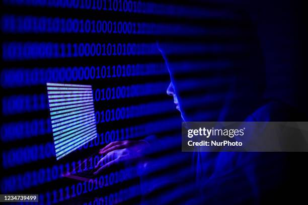 Person dressed as an internet hacker is seen with binary code displayed on a laptop screen in this double exposure illustration photo taken in...