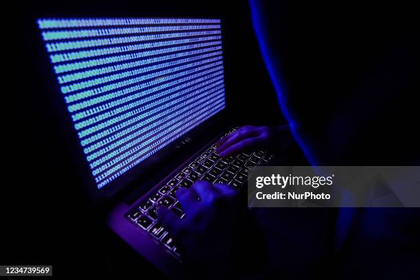 Person dressed as an internet hacker is seen with binary code displayed on a laptop screen in this illustration photo taken in Krakow, Poland on...