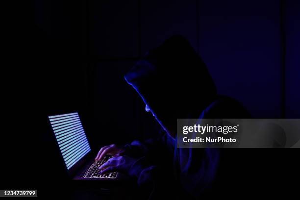Person dressed as an internet hacker is seen with binary code displayed on a laptop screen in this illustration photo taken in Krakow, Poland on...