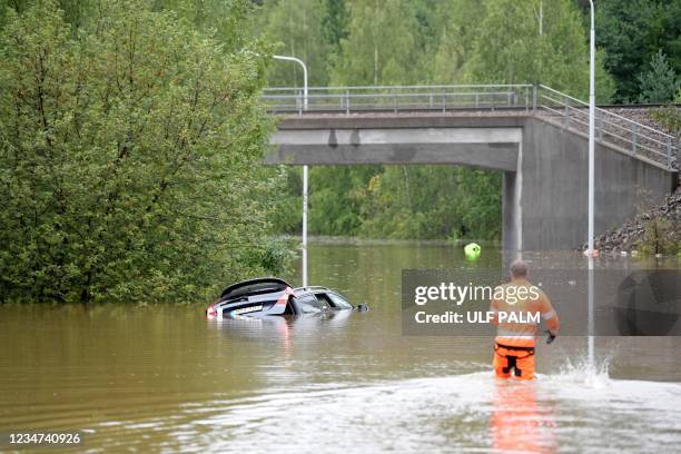 Rescue worker approaches a car partly submerged in water on Källviksvägen in Falun, Sweden, on August 18, 2021 after heavy rains in eastern Sweden...