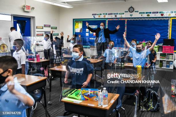 The new Superintendent of Schools for the Archdiocese of Miami, Jim Rigg dances with students wearing facemasks as they attend their first day in...