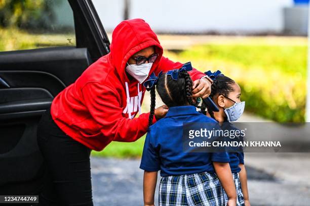 Mother adjusts the facemask of her child as she enters the St. Lawrence Catholic School on the first day of school after summer vacation in north of...