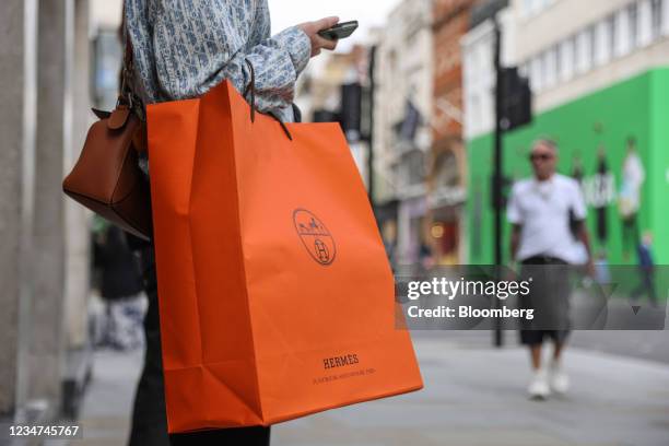 Shopper holds a Hermes International shopping bag on New Bond Street in London, U.K., on Wednesday, Aug. 18, 2021. U.K. Inflation eased in July in...