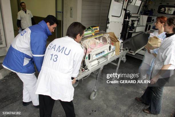 Du personnel médical transporte un bébé prématuré dans une couveuse, le 18 janvier 2005 à Marseille, lors du transfert d'une quinzaine de bébés...