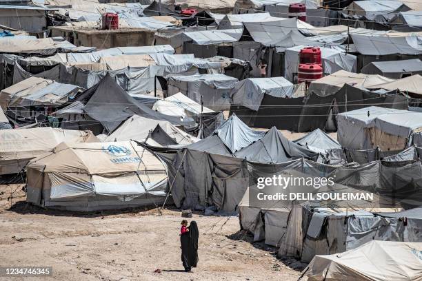 Woman walks carrying a child at the Kurdish-run al-Hol camp, which holds relatives of suspected Islamic State group fighters, in Syria's northeastern...