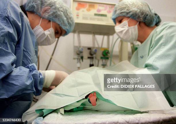Des infirmières posent le 20 février 2003, un cathéter veineux ombilical à un bébé prématuré dans une couveuse du service de néonatalogie de...