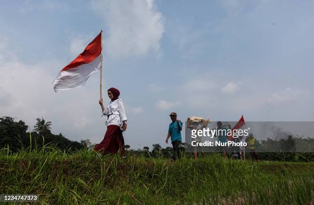 Group farmers and child walk amongst paddy fields during celebrate 76th Indonesian Independence Day at Mulyaharja in Bogor, West Java, Indonesia, on...