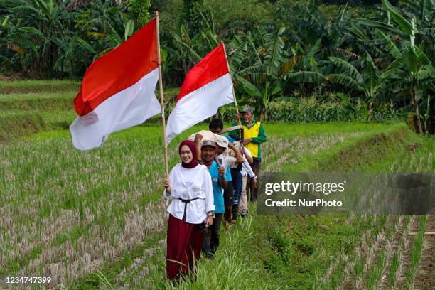 Group farmers and child walk amongst paddy fields during celebrate 76th Indonesian Independence Day at Mulyaharja in Bogor, West Java, Indonesia, on...