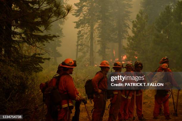 Inmate firefighters from the Antelope Conservation Camp wait for their next assignment as they work to contain the Dixie Fire among burning trees on...