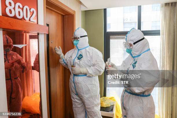 Medical staff members wearing personal protective equipment against the spread of Covid-19 coronavirus knock on a door as they collect samples to be...