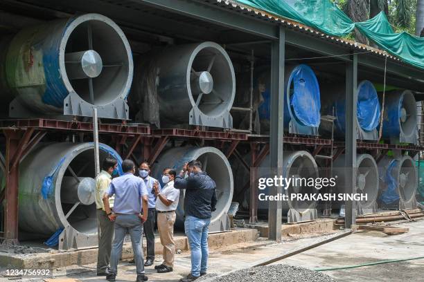 Officials talk next to large fans at the construction site of a 25-metre high smog tower near Connaught Place in New Delhi in New Delhi on August 19,...