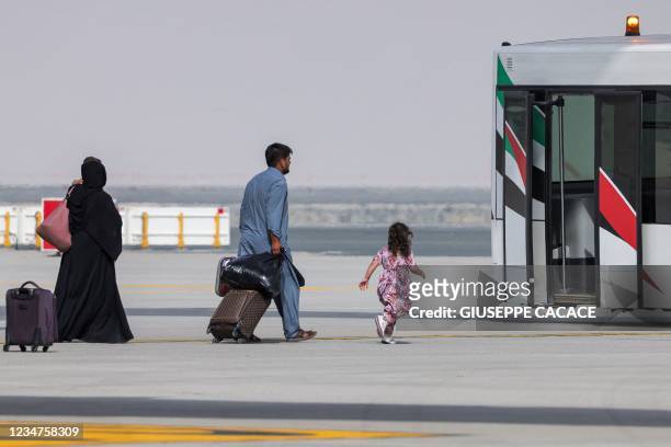 Girl runs towards an airport shuttle bus as people disembark off a Royal Air Force military transport aircraft carrying evacuees from Afghanistan and...