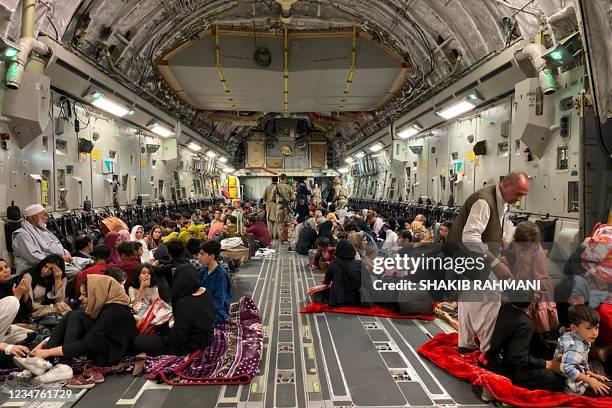 Afghan people sit inside a U S military aircraft to leave Afghanistan, at the military airport in Kabul on August 19, 2021 after Taliban's military...