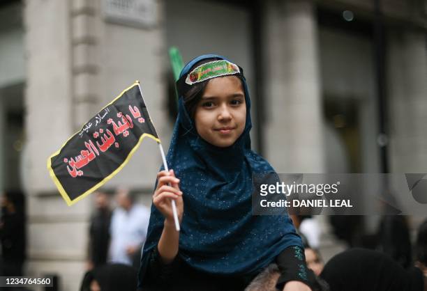 Girl holds a flag as Shiite Muslims take part in the annual 'Ashura Day' march in central London on August 19, 2021. - Shiite Muslims, on the tenth...