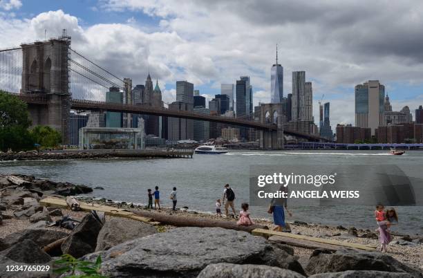 People play at a small beach in Brooklyn Bridge Park in the Dumbo neighborhood of New York City on August 19, 2021. - President Joe Biden's...