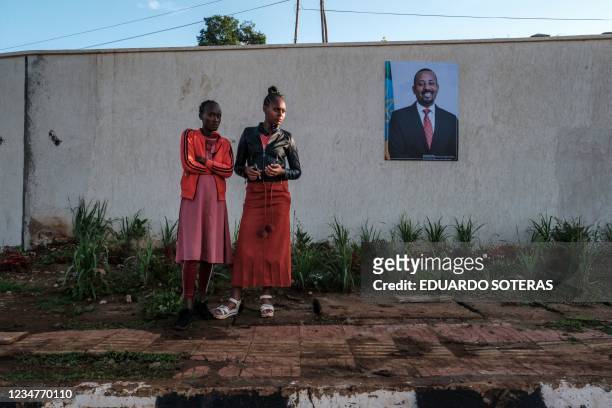 People stand next to a sign depicting Ethiopias Prime Minister Abiy Ahmed at the entrance to Bonga University, in the town of Bonga, 100 kms...