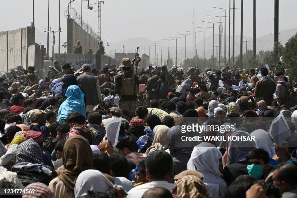 Afghans gather on a roadside near the military part of the airport in Kabul on August 20 hoping to flee from the country after the Taliban's military...