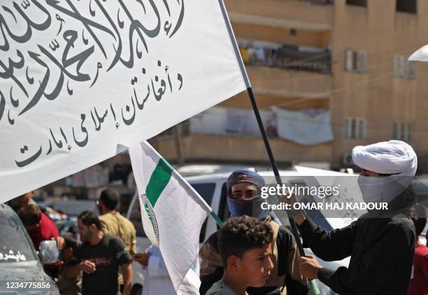 Members of Syria's top jihadist group the Hayat Tahrir al-Sham alliance, led by al-Qaeda's former Syria affiliate, parade with their flags and those...