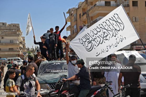 Members of Syria's top jihadist group the Hayat Tahrir al-Sham alliance, led by al-Qaeda's former Syria affiliate, parade with their flags and those...