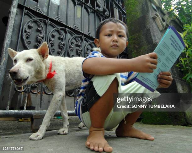 Child holds his dog's certificate after his pet was vaccinated against rabies in Denpasar on October 29, 2010 during the province-wide anti-rabies...