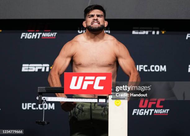 In this UFC handout, Kelvin Gastelum poses on the scale during the UFC Fight Night weigh-in at UFC APEX on August 20, 2021 in Las Vegas, Nevada.