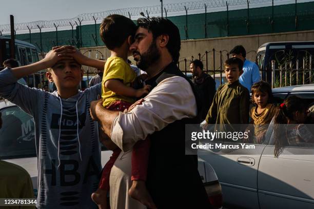 Father rests his head on his childÕs face as his elder son puts both his hands on his head in despair on the road to the military entrance of the...