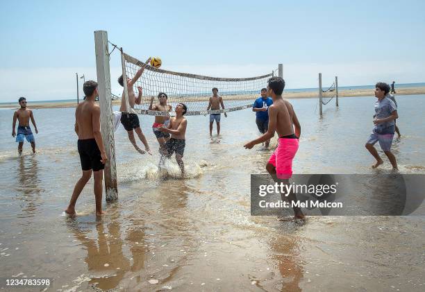 Students from Glendale Academy High School play volleyball in an area that is normally sand but became flooded with ocean water due to a combination...