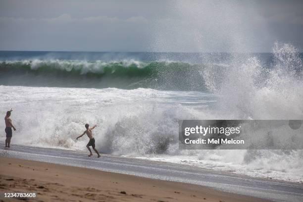 Tom Zilligen left, and his son Daniel react to the high surf at Zuma Beach in Malibu. They are visiting from Highland Ranch, Colorado.