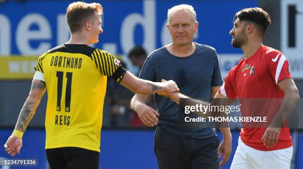 Freiburg's German head coach Christian Streich looks on as Dortmund's German forward Marco Reus shakes hands with Freiburg's Italian midfielder...