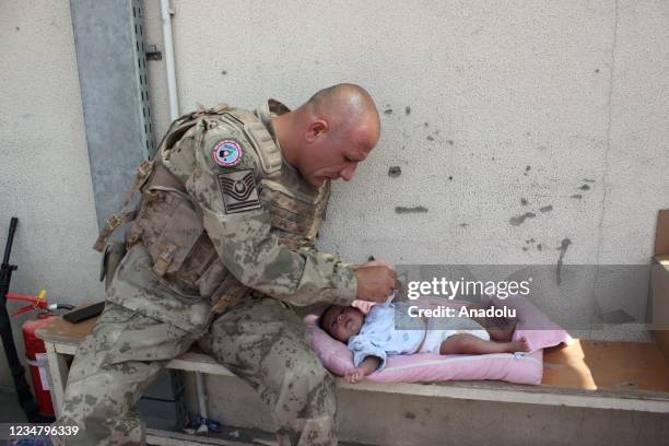 Turkish soldier takes care of a baby as people waiting for evacuation at Hamid Karzai International Airport in Kabul, Afghanistan on August 21, 2021.