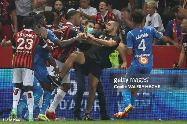Marseille's French midfielder Dimitri Payet reacts as players from OGC Nice and Olympique de Marseille stop a fan invading the pitch trying to kick...