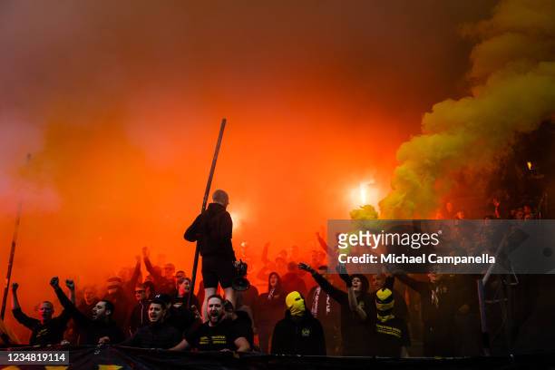 Supporters waves flags and light flares during the Allsvenskan match between AIK and BK Hacken at Friends Arena on August 22, 2021 in Stockholm,...