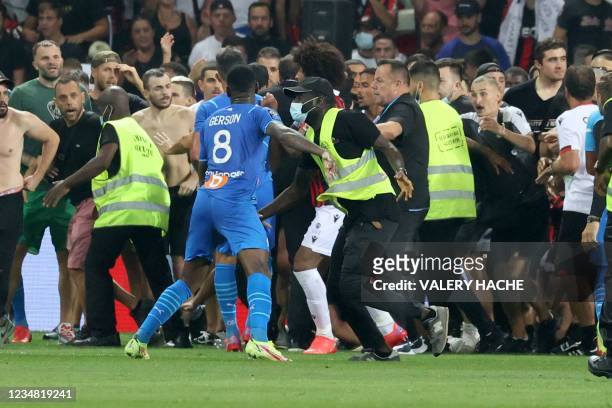 Security try to prevent fans as they invade the pitch during the French L1 football match between OGC Nice and Olympique de Marseille at the Allianz...