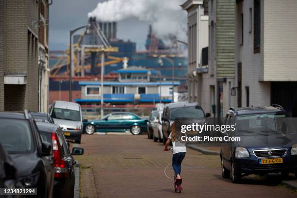 Fchild on a scooter in a residential area near the Tata Steel plant on August 22, 2021 in Ijmuiden. The Tata steel plant is under investigation by...
