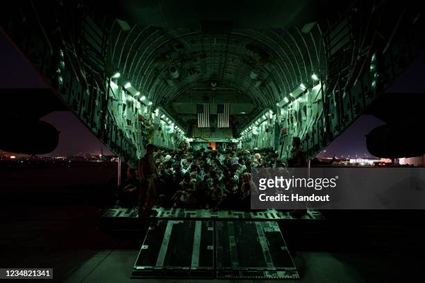 In this handout provided by the U.S. Air Force, an air crew assigned to the 816th Expeditionary Airlift Squadron assists evacuees aboard a C-17...