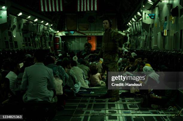 In this handout provided by the U.S. Air Force, a loadmaster assigned to the 816th Expeditionary Airlift Squadron assists evacuees aboard a C-17...