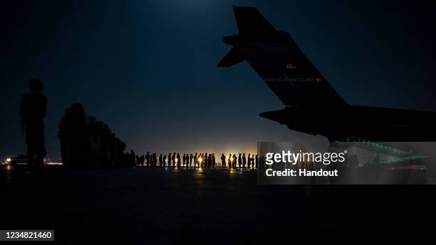 In this handout provided by the U.S. Air Force, an air crew prepares to load evacuees aboard a C-17 Globemaster III aircraft in support of the...