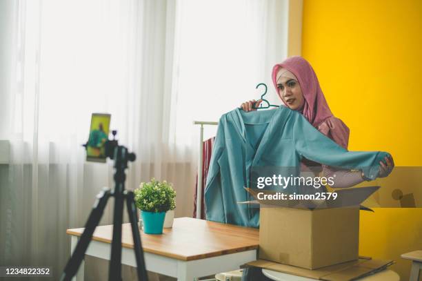 young muslim woman with hijab working live streaming online clothing store at home - live event business stock pictures, royalty-free photos & images