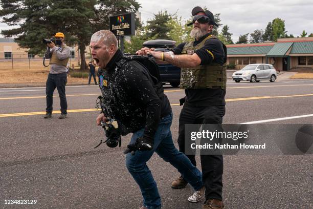 Two members of the far-right group Proud Boys react to an attack by left-wing counter protesters on August 22, 2021 in Portland, Oregon. The Proud...