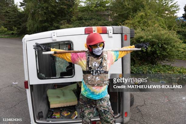Far-right activist stands in front of a flipped-over van after an altercation with anti-fascist activists following a far-right rally on August 22,...