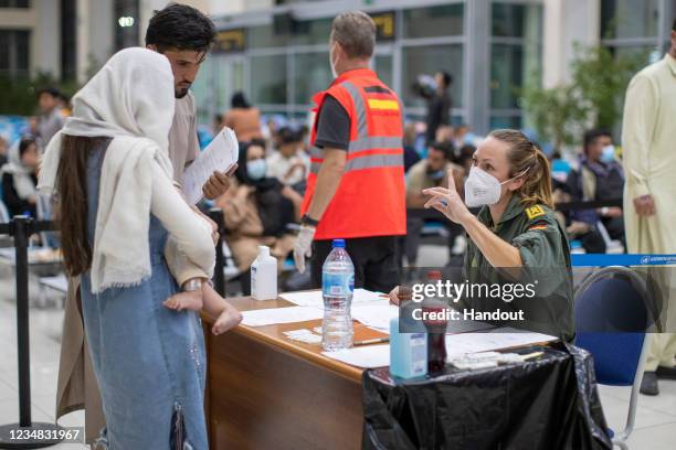 In this handout image provided by the Bundeswehr, an arriving family from Afghanistan are seen registering for a Coronavirus test with a member of...