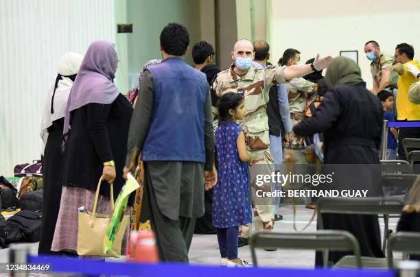 French soldier gestures as people wait in a reunion and evacuation center at the French military air base 104 of Al Dhafra, near Abu Dhabi, on August...